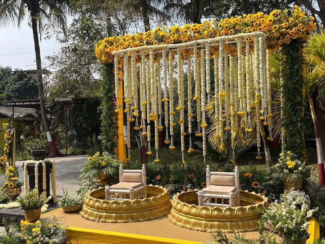 Indian wedding décor with yellow and white florals, hanging garlands and brass accents