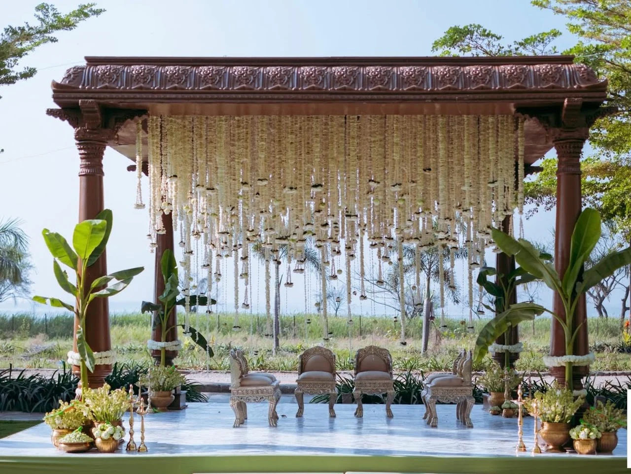 Outdoor wooden wedding mandap with cascading white flowers and ceremony seating