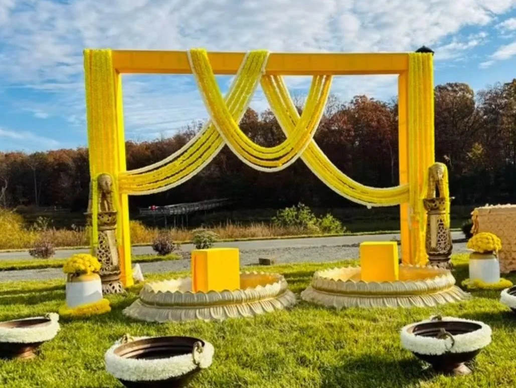 Open-air yellow draped ceremony frame with floral details and garden seating